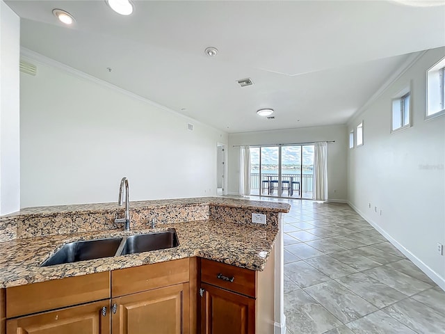 8743 S The Esplanade Unit 18, Orlando, FL 32836 - kitchen with crown molding, dark stone counters, open floor plan, and a peninsula