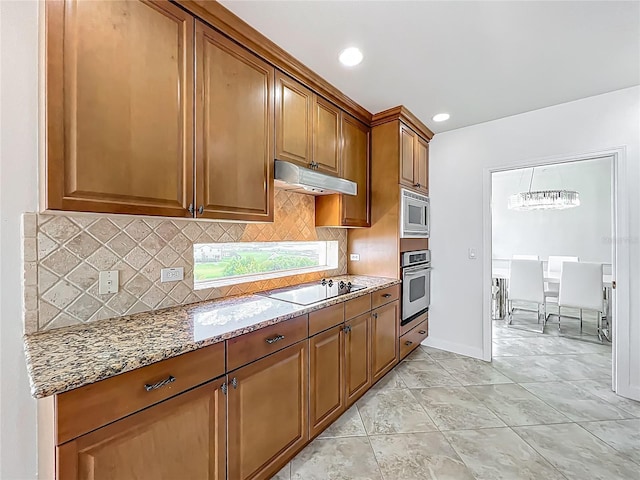 8743 S The Esplanade Unit 18, Orlando, FL 32836 - kitchen featuring stainless steel appliances, light stone counters, under cabinet range hood, brown cabinets, and tasteful backsplash