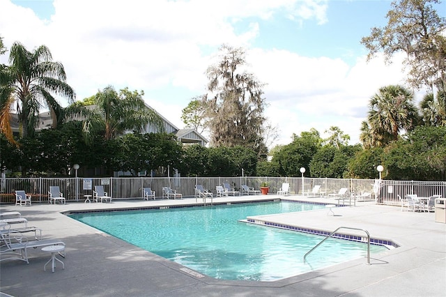 community pool with a patio and fence