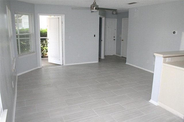 unfurnished room with baseboards, visible vents, and a ceiling fan