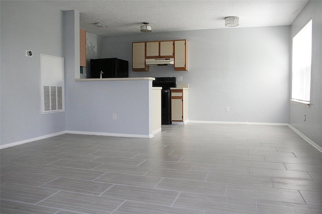 interior space with baseboards, a textured ceiling, visible vents, and a healthy amount of sunlight