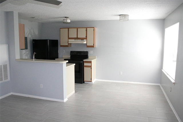 kitchen featuring light countertops, a textured ceiling, under cabinet range hood, visible vents, and black appliances