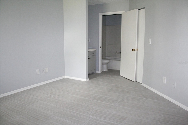 unfurnished bedroom with baseboards and connected bathroom