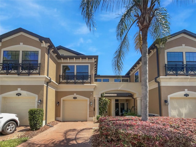 view of front of property featuring a balcony, driveway, stucco siding, and an attached garage