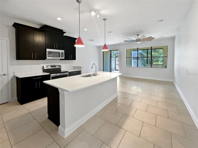kitchen with light countertops, a ceiling fan, a center island with sink, appliances with stainless steel finishes, and a sink