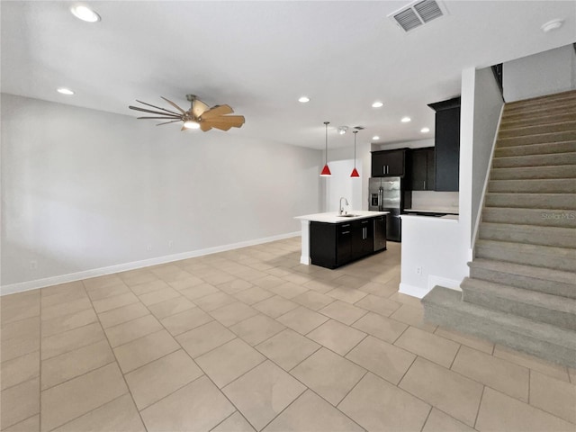 kitchen with open floor plan, stainless steel fridge with ice dispenser, visible vents, a ceiling fan, and a kitchen island with sink