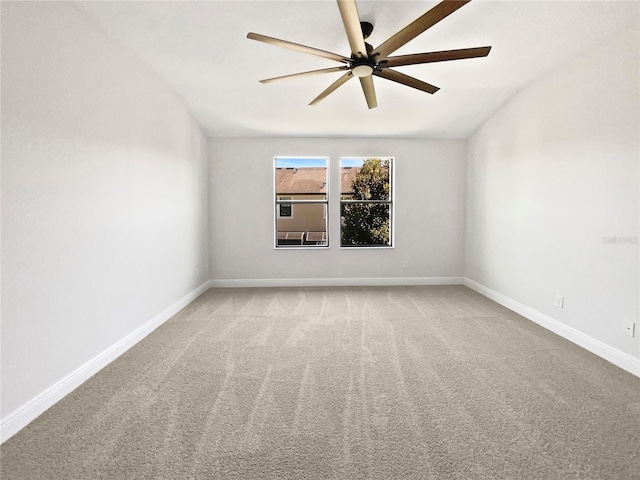 spare room with baseboards, ceiling fan, vaulted ceiling, and light carpet