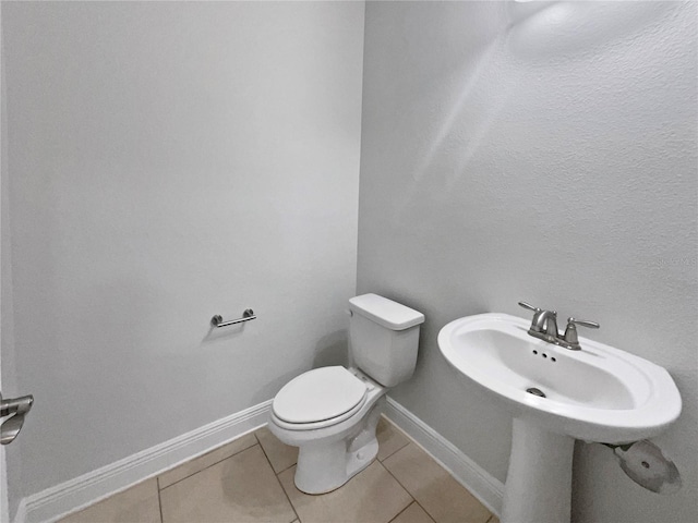 half bathroom with tile patterned floors, toilet, and baseboards