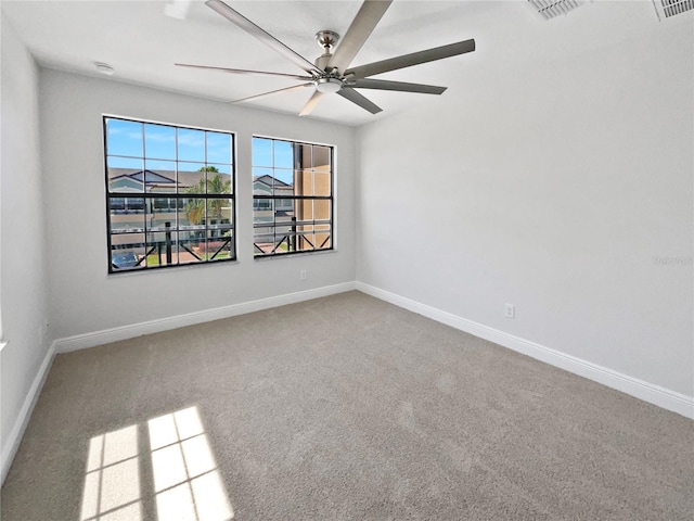 carpeted spare room with visible vents, baseboards, and ceiling fan