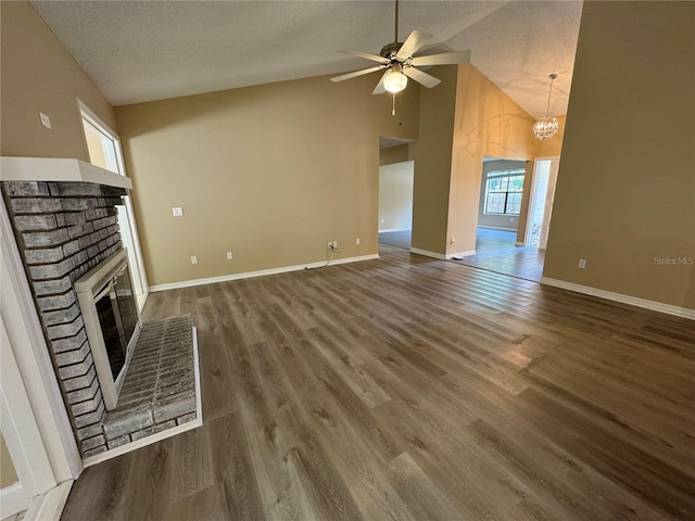 2132 Majestic Woods Blvd, Apopka, FL 32712 - unfurnished living room with a textured ceiling, baseboards, a fireplace, wood finished floors, and ceiling fan with notable chandelier