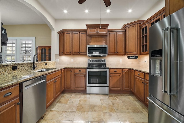 kitchen with tasteful backsplash, arched walkways, a sink, and stainless steel appliances