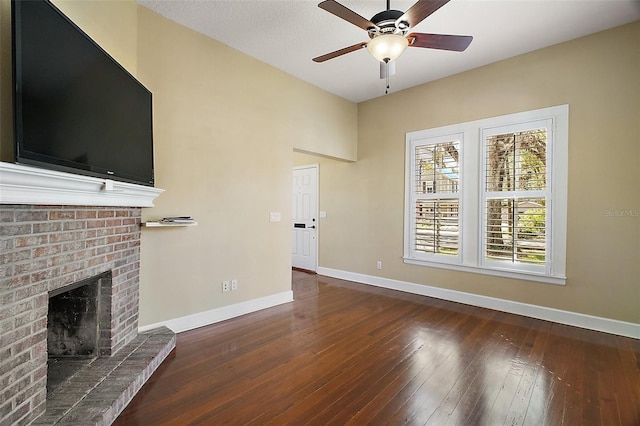 unfurnished living room featuring hardwood / wood-style floors, baseboards, a ceiling fan, and a brick fireplace