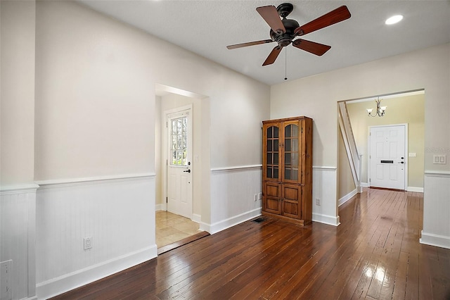 empty room featuring hardwood / wood-style flooring, wainscoting, baseboards, ceiling fan with notable chandelier, and recessed lighting