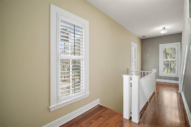 hall featuring baseboards, an upstairs landing, visible vents, and dark wood finished floors