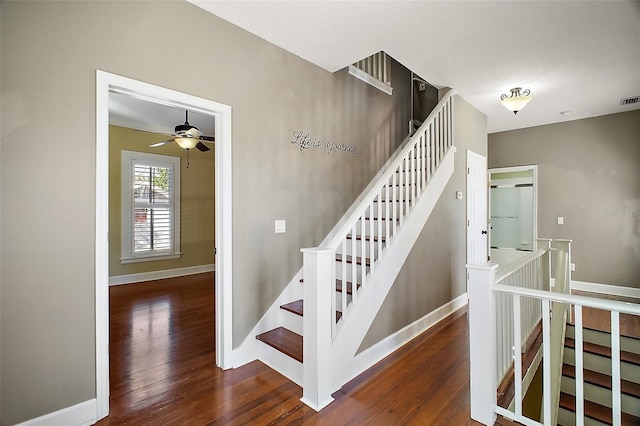 staircase featuring baseboards, visible vents, ceiling fan, and wood finished floors