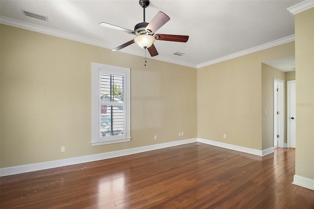 spare room featuring dark wood-style floors, visible vents, crown molding, and baseboards