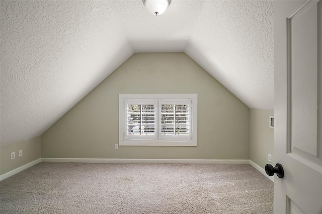 additional living space featuring baseboards, vaulted ceiling, carpet floors, and a textured ceiling