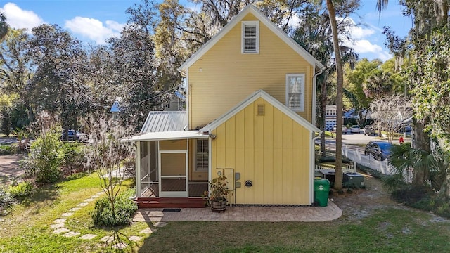rear view of property featuring a sunroom and metal roof