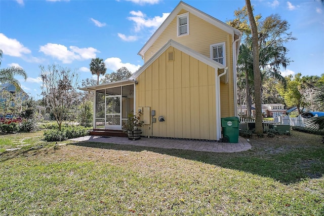 rear view of property featuring a lawn and a sunroom