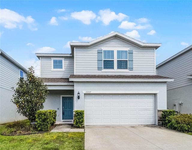 traditional-style house featuring an attached garage, a shingled roof, concrete driveway, and stucco siding