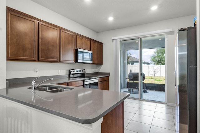 kitchen with recessed lighting, light tile patterned floors, dark countertops, stainless steel appliances, and a sink