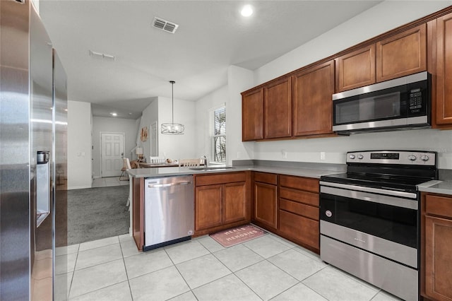 kitchen featuring a peninsula, visible vents, brown cabinets, appliances with stainless steel finishes, and a sink