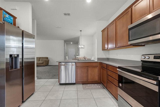 kitchen with a sink, open floor plan, a peninsula, brown cabinetry, and stainless steel appliances