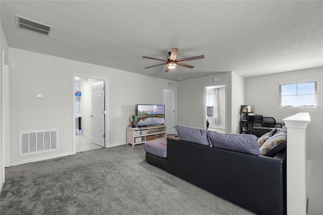 carpeted living room with a textured ceiling, a ceiling fan, and visible vents