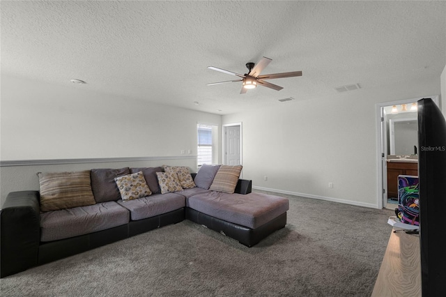 carpeted living room with a textured ceiling, baseboards, a ceiling fan, and visible vents