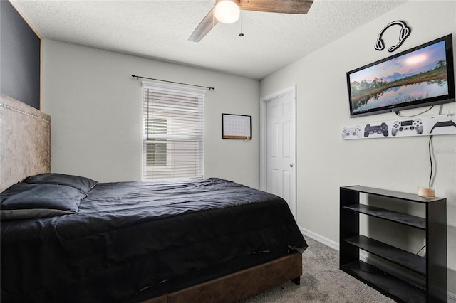 bedroom featuring a textured ceiling, carpet flooring, baseboards, and a ceiling fan