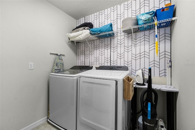 clothes washing area with laundry area, baseboards, washing machine and dryer, and a textured ceiling