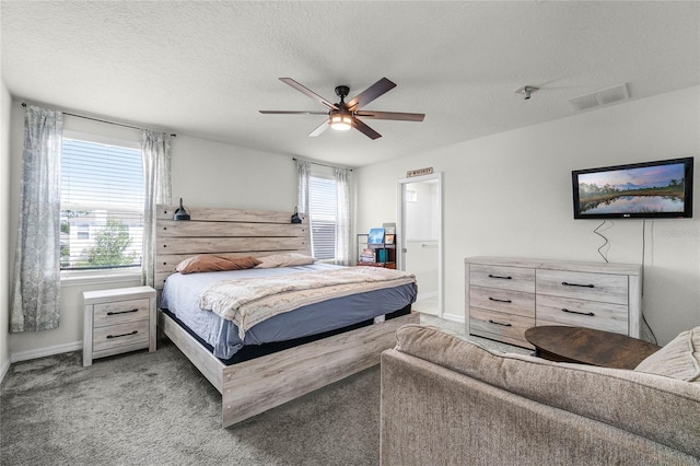 carpeted bedroom featuring a textured ceiling, baseboards, a ceiling fan, and visible vents