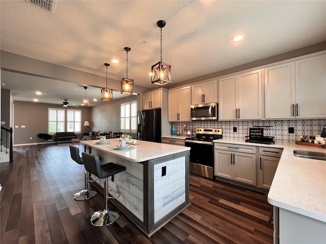 kitchen with decorative backsplash, appliances with stainless steel finishes, visible vents, dark wood-style flooring, and open floor plan