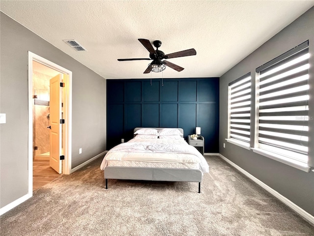 carpeted bedroom with baseboards, visible vents, a ceiling fan, and a textured ceiling