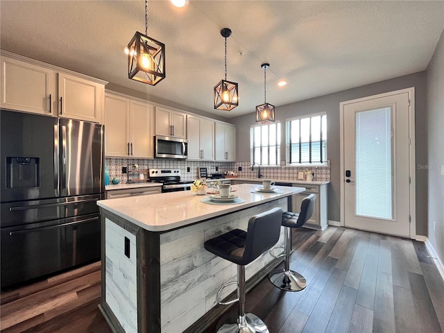 kitchen featuring a center island, stainless steel appliances, backsplash, and light countertops