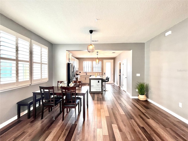 dining area featuring dark wood-style floors, baseboards, and a textured ceiling