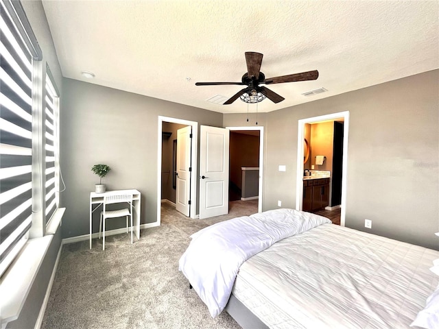 bedroom featuring a walk in closet, a textured ceiling, visible vents, and baseboards