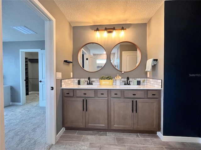 full bath with a textured ceiling, tasteful backsplash, and a sink
