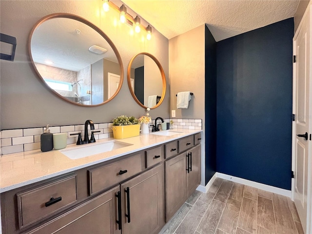 bathroom with double vanity, decorative backsplash, a shower, and a sink