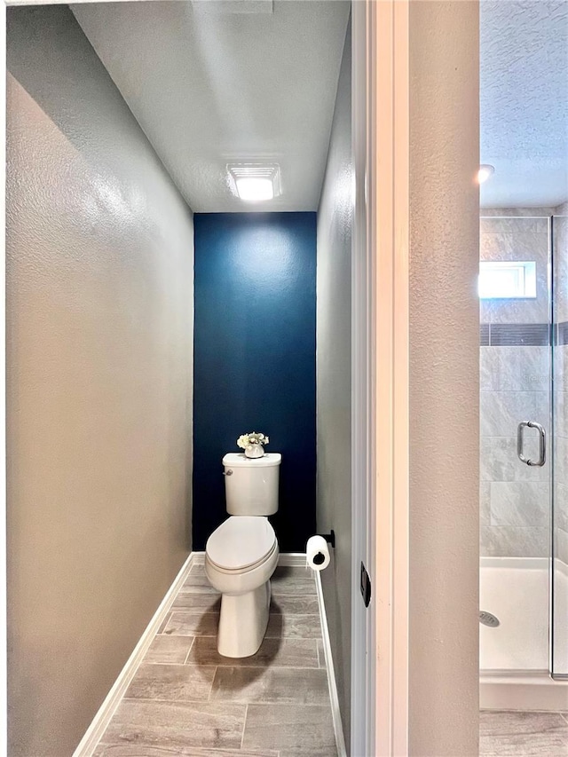 full bathroom featuring toilet, a stall shower, wood finished floors, and baseboards
