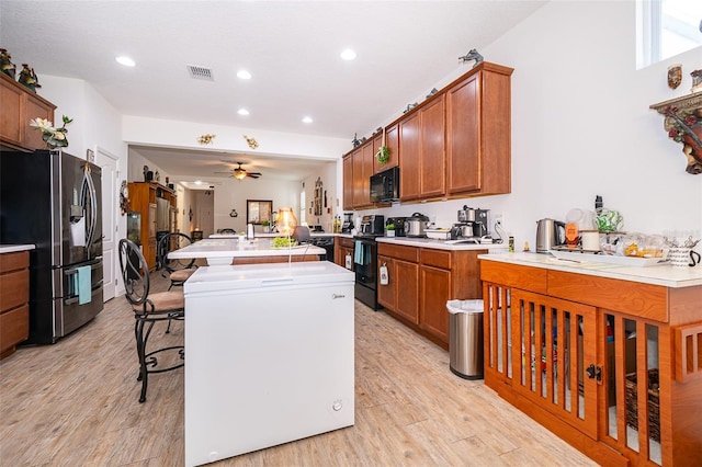 2289 Aloe Aly, Apopka, FL 32703 - kitchen featuring a center island with sink, visible vents, light wood-style floors, light countertops, and black appliances