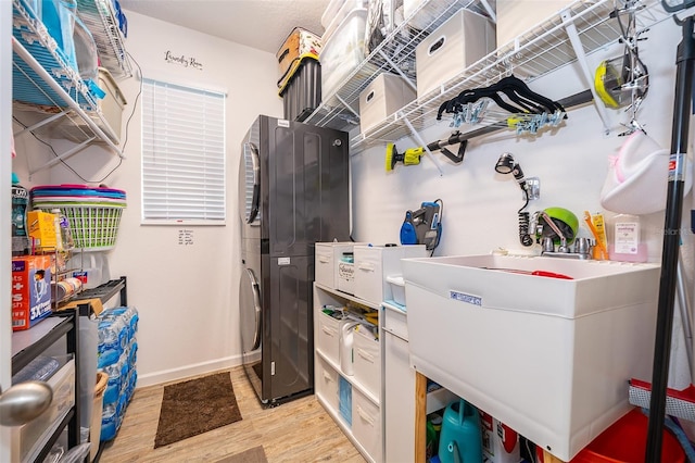 2289 Aloe Aly, Apopka, FL 32703 - clothes washing area with light wood finished floors, a sink, baseboards, stacked washing maching and dryer, and laundry area