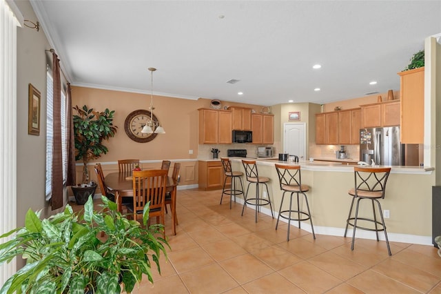 920 Nola Dr, Ocoee, FL 34761 - kitchen with stainless steel fridge with ice dispenser, black microwave, a kitchen breakfast bar, a peninsula, and light tile patterned flooring