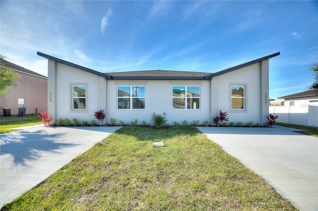 view of front of home with stucco siding, fence, and a front lawn