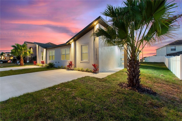 view of front of home featuring fence, stucco siding, and a yard