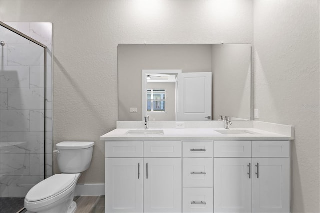 full bath featuring toilet, a sink, a textured wall, and a stall shower