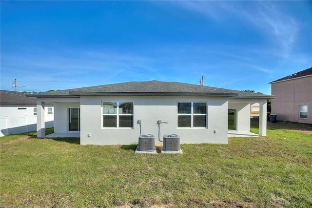back of house with fence, stucco siding, a yard, and central air condition unit