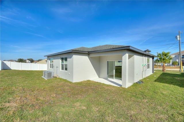 rear view of property featuring central air condition unit, stucco siding, fence, a lawn, and a patio area
