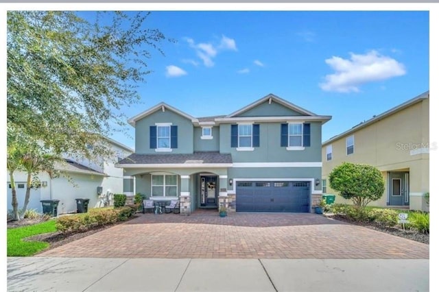 view of front of home with stucco siding, covered porch, a garage, and decorative driveway