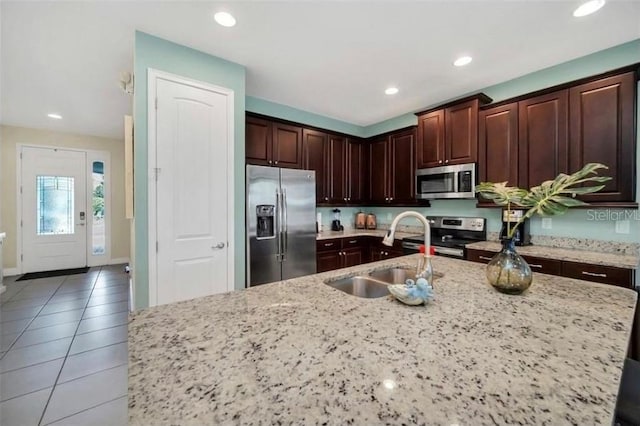 kitchen with a sink, light stone countertops, light tile patterned floors, stainless steel appliances, and recessed lighting